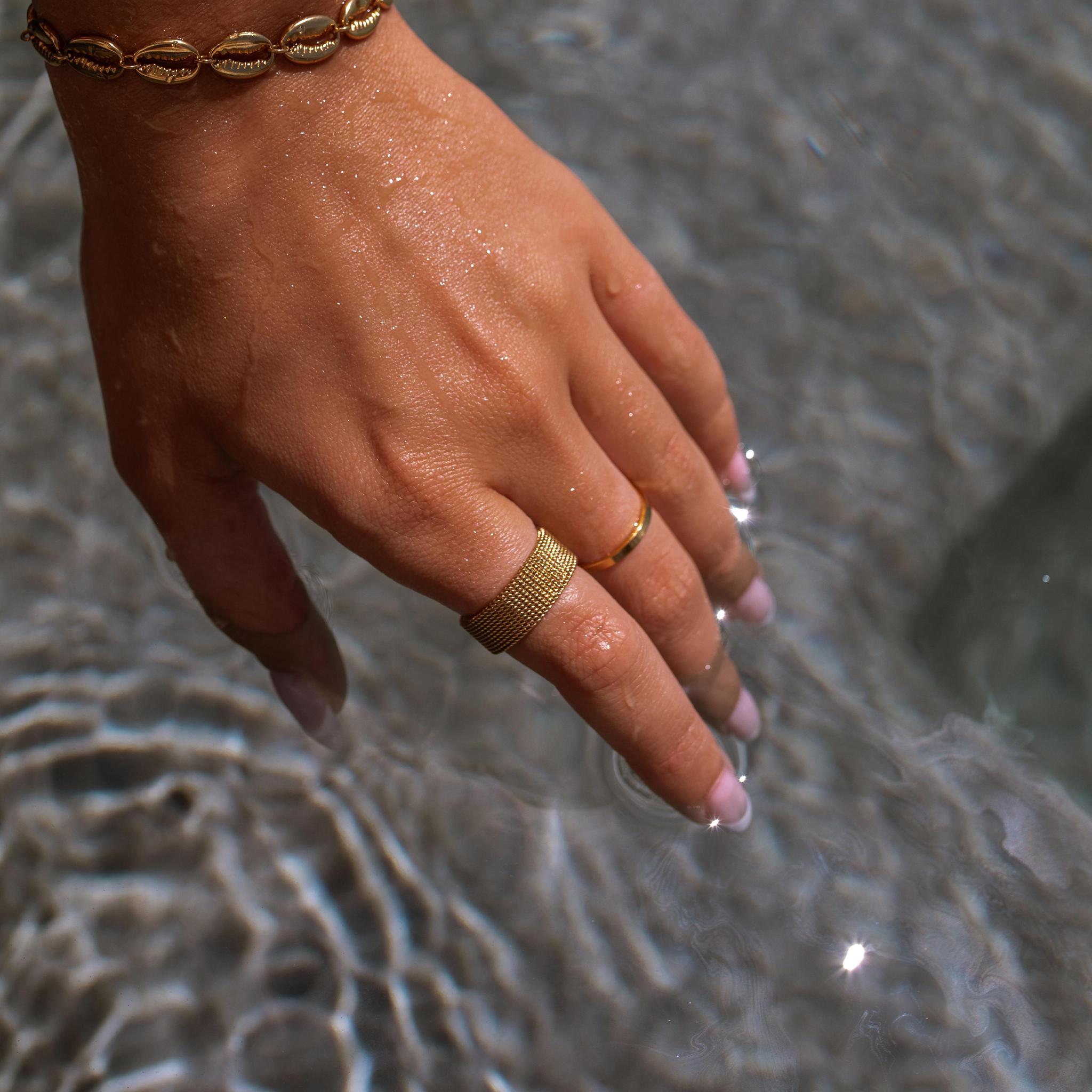 Gold water resistant rings by ALCO Jewelry reaching into pool water