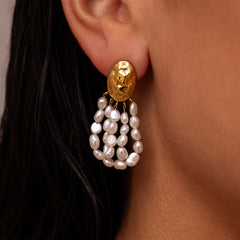 Unique gold earring with freshwater pearl drops in the shape of a fan on a textured gold oval stud worn by a woman