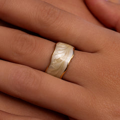 Iridescent ring with wavy gold rim and pearlescent sand resin in the center